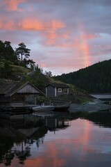 Fototapeta premium Vertical of wooden houses on shore of a lake at sunset