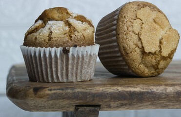 Two freshly-baked muffins atop a wooden cutting board, one muffin slightly overlapping the other