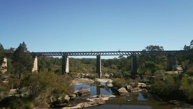 Drone footage under the Quart Pot Creek Rail Bridge with forest trees in Stanthorpe, Australia