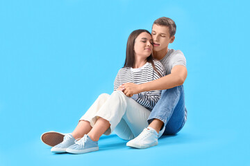 Fototapeta na wymiar Happy young couple hugging on blue background