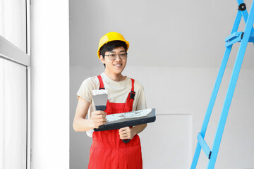 Asian decorator with putty knives in room