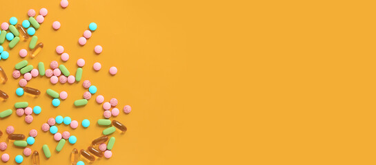 Vitamins of different colors on a yellow background. Top view of scattered bright pills....