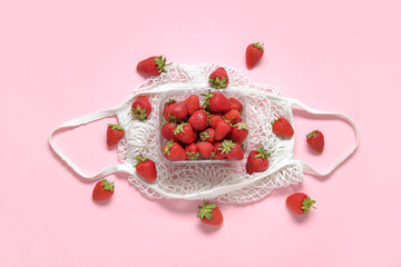Mesh bag with fresh strawberry in plastic container on pink background