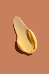 Yellow cosmetic smear of cream texture on a coral background. Skin care.