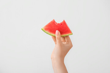 Female hand with bitten piece of ripe watermelon on white background