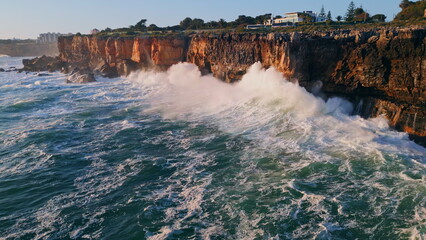 Powerful ocean water crashing on rocky seashore with huge splashes. Stormy sea