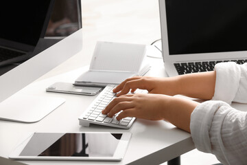 Female programmer typing on computer keyboard at her workplace in office, closeup