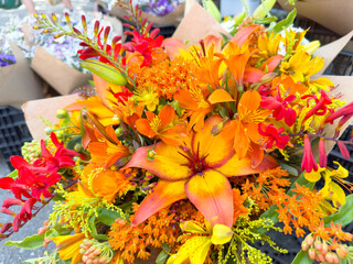 A view of an orange yellow flower bouquet, on display at a local farmers market.