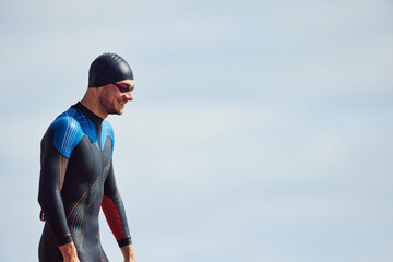 male swimmer in wet suit against blue sky