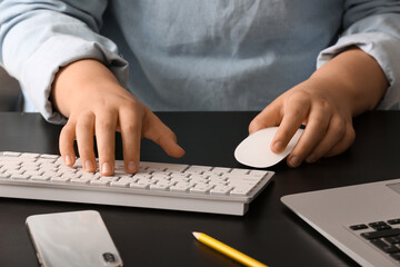Female programmer typing on computer keyboard at her workplace in office, closeup