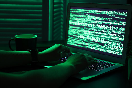 Female programmer typing on laptop keyboard at night in office, closeup