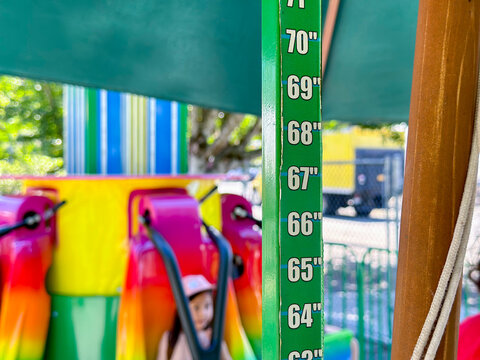 A view of a height ruler, seen at the entrance to a children's carnival ride.