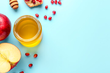 Obraz na płótnie Canvas Jar of honey with apples and pomegranate seeds for Rosh Hashanah celebration (Jewish New Year) on blue background