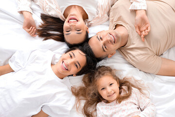 Little children with their parents lying on bed, top view