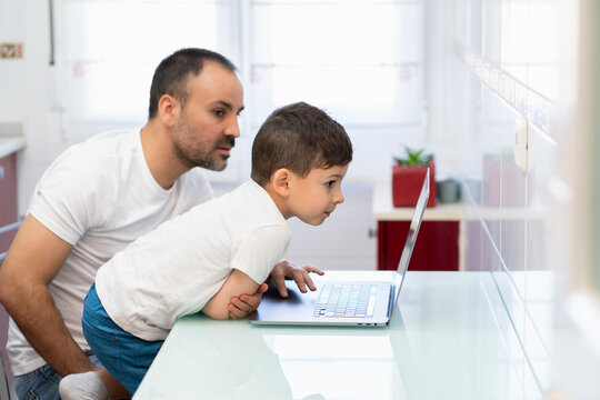 Father using laptop near curious son
