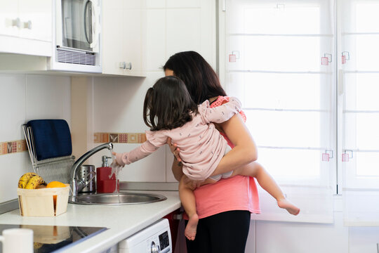 Mother and daughter washing hands in kitchen