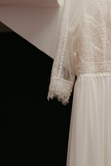 the wedding dress hangs in the room by the window that is closed