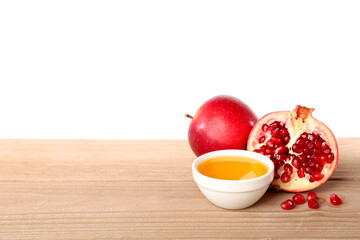 Bowl of sweet honey, ripe apple and pomegranate on wooden table against white background