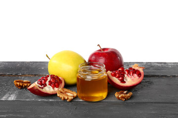 Jar of sweet honey, ripe fruits and walnuts on dark wooden table against white background