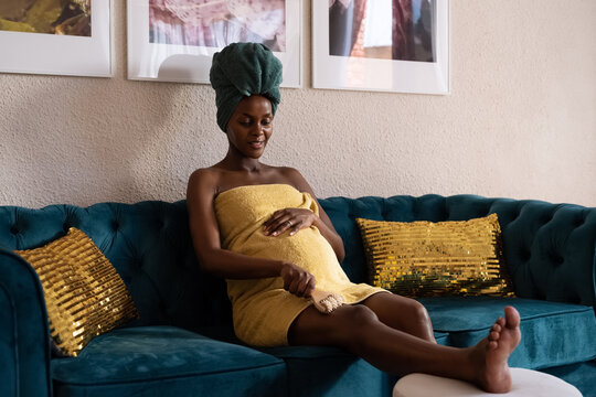 Smiling black future mother massaging leg