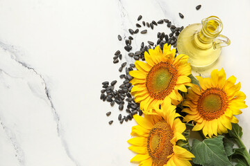 Beautiful sunflowers, seeds and decanter of oil on grunge white background