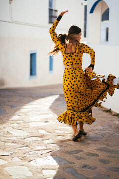 Woman dancing on sunny street and holding skirt