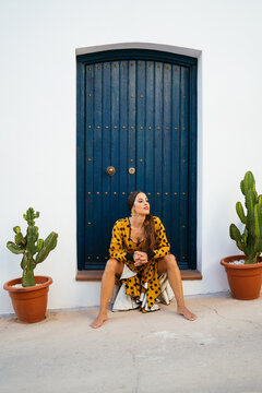 Barefooted stylish woman resting in yard of house