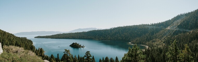 a lake surrounded by green trees on top of a hill