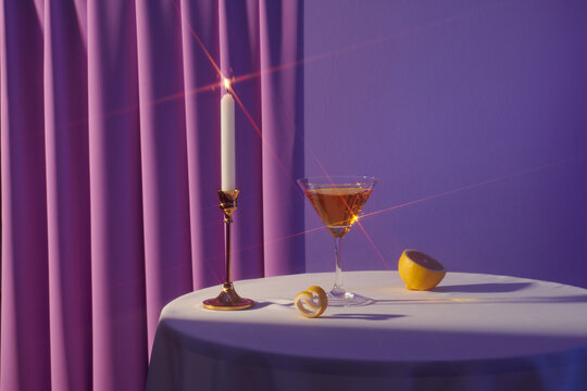 A martini cocktails with a slice of lemon and a candle
