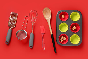 Baking forms and utensils on red background