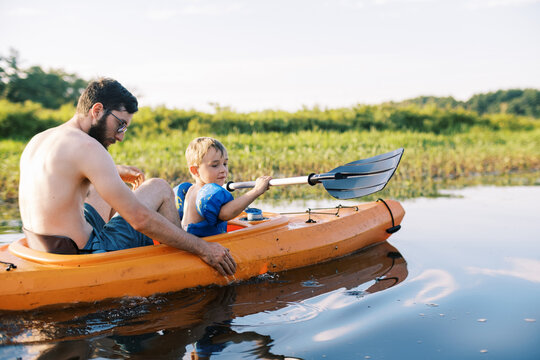 father and son kayaking together on summer day in massachusetts