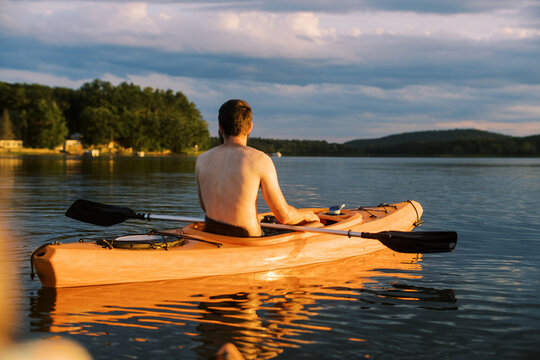 millennial man sitting in kayak during sunset on a lake