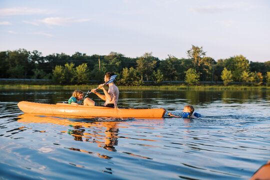 Young dad and his toddler children bathing and kayaking in summer