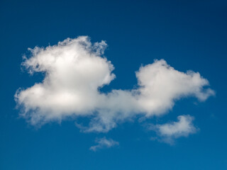 Single white cloud over blue sky background. Fluffy cumulus cloud shape