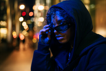 Cool black female in hoodie on night street