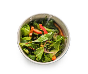 Bowl of fresh salad covered with plastic food wrap on white background