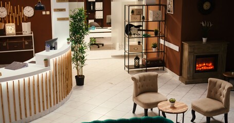 Tilt down shot of posh green sofa and armchairs furniture in empty luxury hotel foyer interior with ready to welcome tourists. Stylish travel vacation accommodation lounge with check in reception