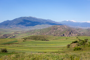 Fototapeta na wymiar Green hills of Lesser Caucasus mountains in Samtskhe - Javakheti region in Georgia with agriculture fields and grasslands.