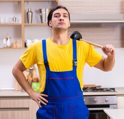 Young male contractor repairing tap at home