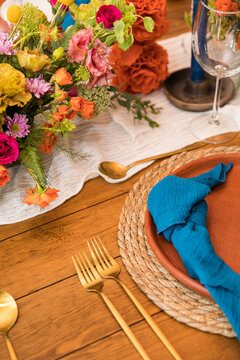 A wooden table set up for a wedding with golden cutlery and flowers
