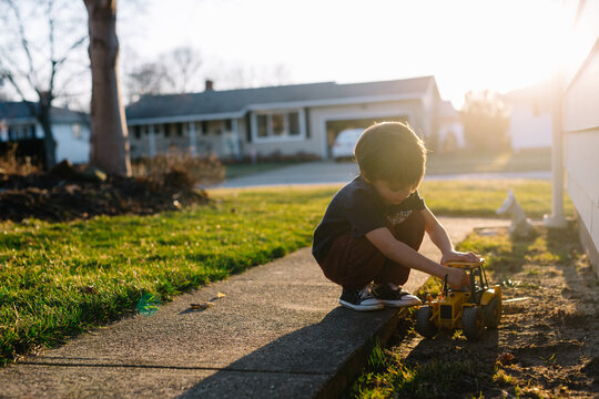 Child plays in dirt on side of house