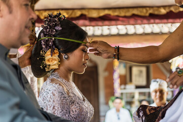 Balinese bride and caucasian groom during multiracial wedding ceremony