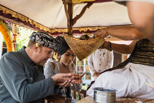 Balinese bride and caucasian groom during multiracial wedding ceremony