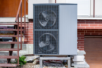 Air-water Heat Pump for Heating and hot Water in Front of a Residential Building. Old house under...