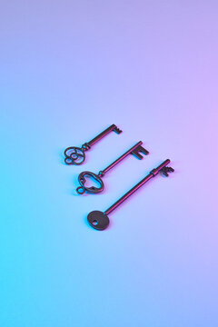 Three ornate keys on neon pink and blue background.