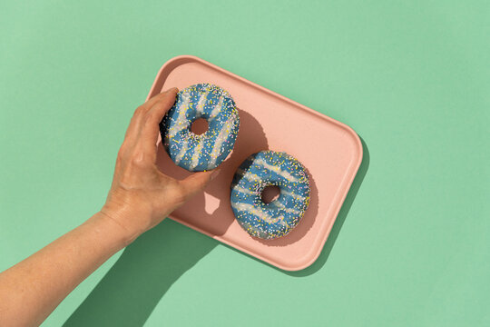 Hand grabbing pastel color donuts 