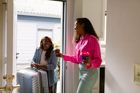 Friend arriving home with suitcase - Powered by Adobe
