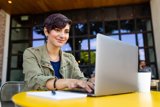 Woman Uses Computer While Having Coffee At Outdoor Cafe In Town