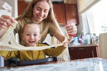 Happy family with child preparing homemade pizza in cozy kitchen