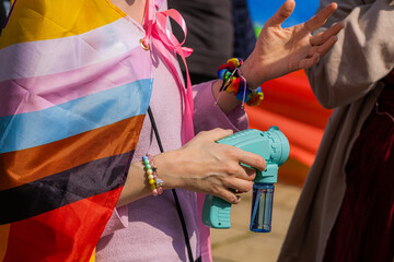 a pride parade participant with a toy gun gestures with his hand